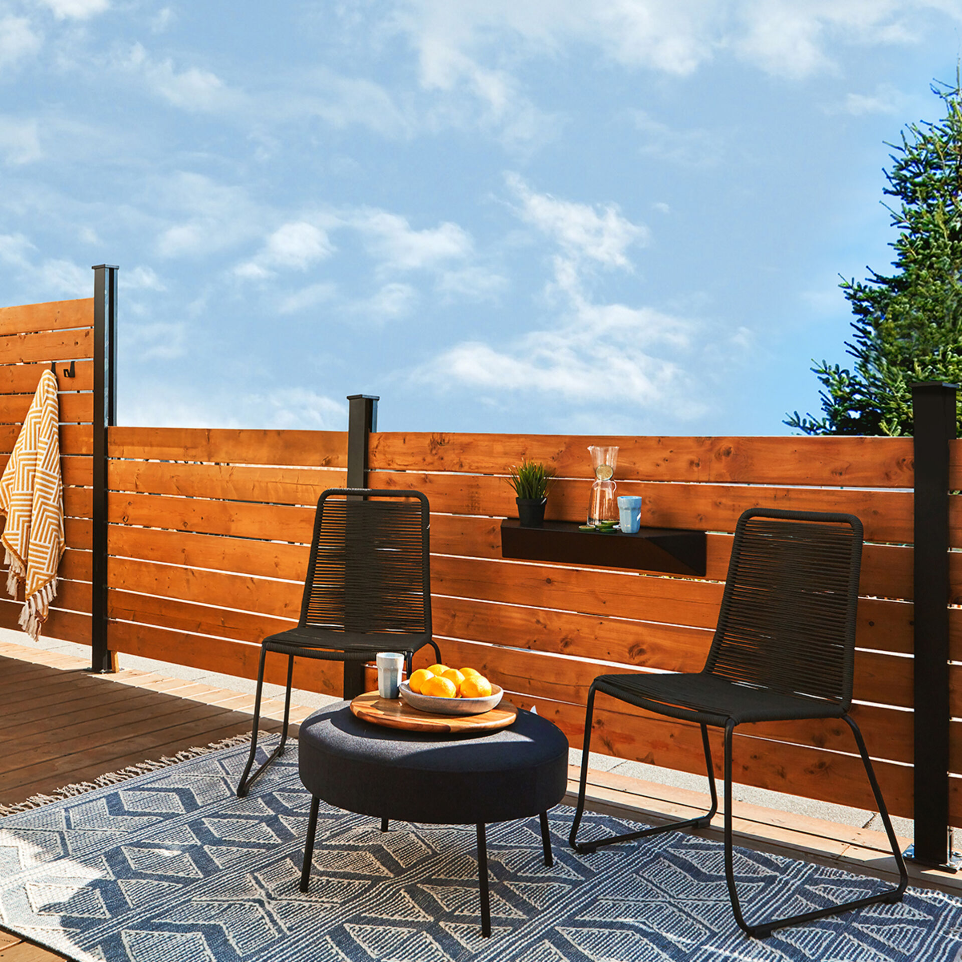 44-beautyshotterrace HOFT 44" Post Kit privacy screen fence creating a modern outdoor patio seating area with horizontal wood panels and black aluminum posts.